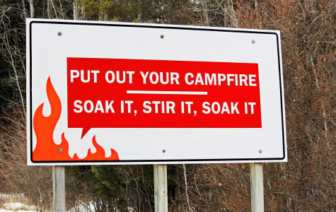 Sign stating "put out your campfire; soak it, stir it, soak it"